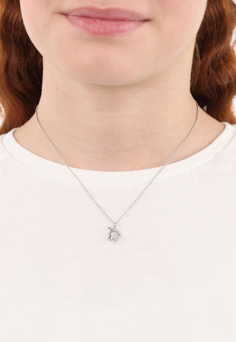 Collana in argento con charm a forma di unicorno, caratterizzata da dettagli intricati e una finitura lucida, indossata sopra una camicia bianca.