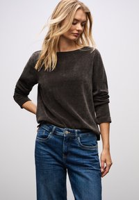 Maglia a maniche lunghe grigia scura con texture e scollatura rotonda, abbinata a jeans in denim blu con un classico design a cinque tasche.