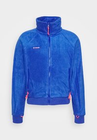 Veste polaire bleue zippée avec col haut, poignets élastiques et tirettes de zip roses, avec petit logo Columbia sur la poitrine.