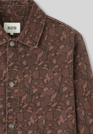 Veste en denim à motifs marron avec un col, boutons-pression en métal argenté et un design abstrait évoquant des roches dans des tons plus clairs.