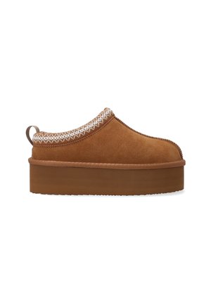 Chausson en daim marron à enfiler avec une épaisse semelle plateforme, présentant une bordure tressée décorative autour du haut et une languette à l'arrière.