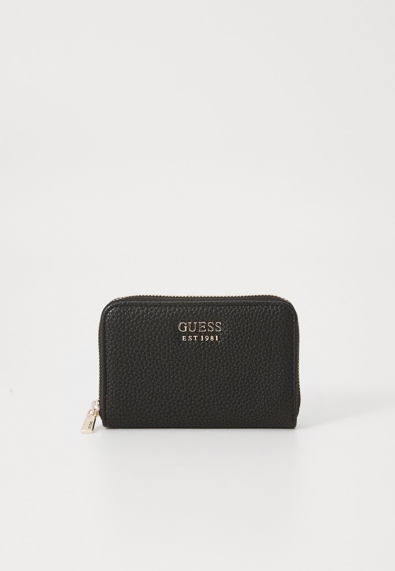 Portafoglio in pelle morbidamente martellata nera, con chiusura a zip, logo dorato "GUESS EST 1981" e una piccola cerniera. Forma rettangolare.