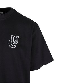 Fekete pamut póló kerek nyakkal, bal mellkason fehér grafikai mintával. Rövid ujjú, sima textúrájú és laza fazonú.