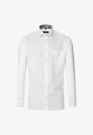 Hvid langærmet skjorte med knapper, der har en lomme på venstre bryst og en mønstret inderside af kraven med blomsterdetaljer. Stofteksturen fremstår glat.