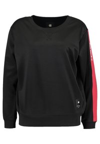 Sudadera negra de manga larga, con puños acanalados y cuello redondo. Presenta una banda de acento roja a lo largo de la manga y una pequeña etiqueta de logo.