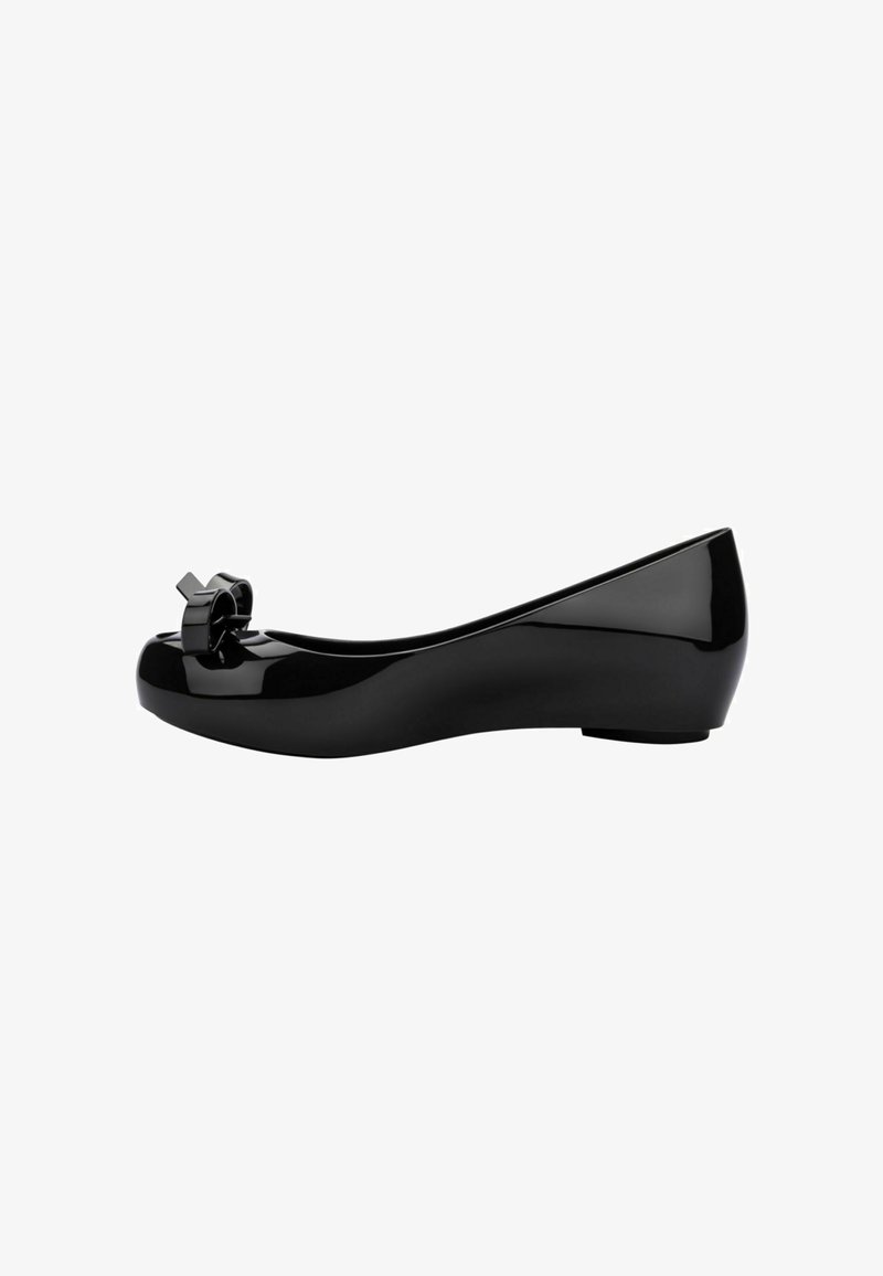 Ballet flat nera con finitura lucida, punta arrotondata e un nastro decorativo davanti. Design elegante con tacco basso.