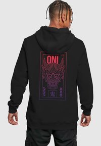 Felpa nera con cappuccio caratterizzata da una grande grafica di una maschera oni stilizzata in un gradiente di rosso e viola. Testo "ONI" in lettere grasse sopra il design.