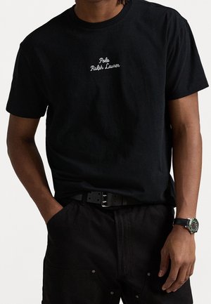 Musta puuvillainen t-paita, jossa pyöreä pääntie ja valkoinen kirjailtu "Polo Ralph Lauren" -logo rinnassa. Rentoa istuvuutta, lyhyet hihat.