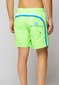 Costume da bagno verde neon con strisce laterali blu e bianche, vita elastica e una tasca sul retro con una patch del logo. Tessuto strutturato.