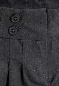 Pantaloni din material negru, cu două butoane negre la talie, cu un design plisat și o textură netedă.