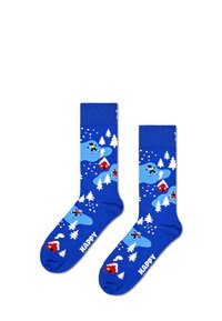 Modré ponožky s zimní scénou, na které jsou stromy, domy a lyžaři. Vyrobeny z měkkého materiálu, mají vyztuženou patu a špičku.