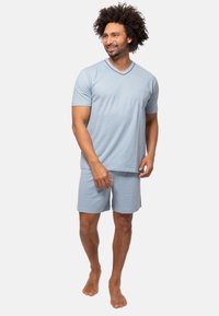 Ljust blå bomullsloungewear-set bestående av en V-ringad kortärmad topp med bröstficka och matchande shorts, avslappnad passform med mjuk textur.