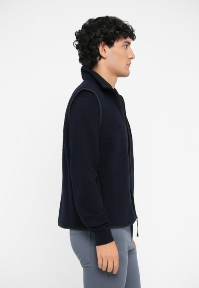 Marineblaue Fleece-Weste mit hohem Kragen und Reißverschluss, ausgestattet mit kontrastierenden Stoffen an den Schultern und einer strukturierten Oberfläche.