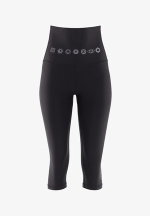 Mustad kõrge vöökoha ja capri lõikega mustad retuusid, millel on valged trükitud tšakra sümbolid vöö ümber, valmistatud venivast kangast.