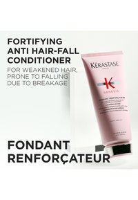 Kérastase Genesis versterkende anti-haaruitval conditioner in een roze tube, met zilveren accenten en een zwarte dop, staat tegen een lichte achtergrond.