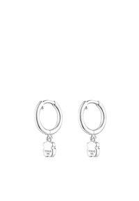 Orecchini a cerchio in argento con piccoli ciondoli a forma di orso incisi con "TOUS S925" appesi a ciascun cerchio.
