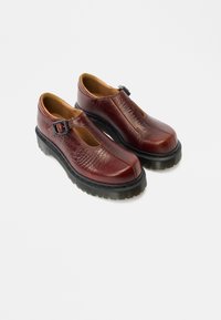 Burgundské kožené topánky s textúrovaným povrchom, vybavené prackou, zaoblenou špičkou a hrubými čiernymi gumovými podrážkami.