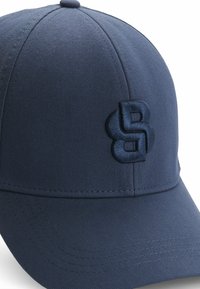Cappellino da baseball blu navy con un design strutturato, realizzato in tessuto testurizzato, con un logo ricamato sulla parte anteriore.