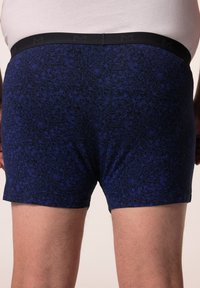 Marineblauwe boxershorts met een bloemenmotief en een zwarte elastische tailleband met reliëfbranding. Zachte stof met een gladde textuur.