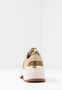 Baskets beiges en cuir texturé, accents dorés et semelle blanche épaisse. Dotées d'une languette à talon pour faciliter l'enfilage.