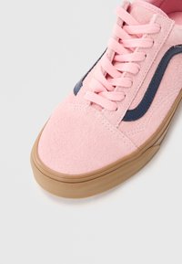 Roze suede tenisice s gumenim potplatom boje karamele, odgovarajućim ružičastim vezicama i detaljem od tamnoplave boje sa strane.