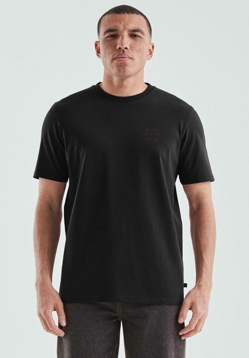 Czarny bawełniany t-shirt z krótkim rękawem, okrągłym dekoltem i małym graficznym napisem na lewej piersi. Płaskie wykończenie i luźny krój.