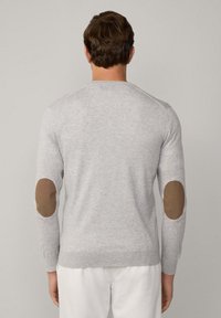 Suéter de punto gris con parches de codo marrones, corte slim, cuello redondo y puños de canalé. Textura suave con costuras detalladas.