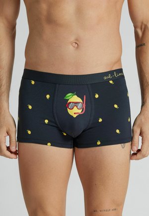 Męski tors w czarnych bokserkach z motywem cytryny i dużą grafiką cytryny z wyposażeniem do nurkowania na środku z przodu.