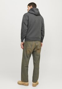 Grå hettegenser med ribbestrikkede mansjetter, parret med olivengrønne straight-leg jeans og brune sko. Teksturen er myk og uformell.