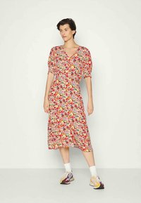 Vestido floral com decote em V, mangas bufantes e comprimento midi. O tecido exibe um padrão colorido de flores sobre um fundo claro.