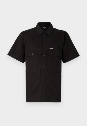 Chemise noire à manches courtes en coton, avec une fermeture à boutons sur le devant, deux poches poitrine et une petite étiquette logo sur la poche gauche.
