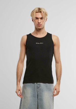 Svart bomullstopp med rund hals, som har en liten hvit brodert logo på brystet og brukes sammen med lyseblå denimshorts.