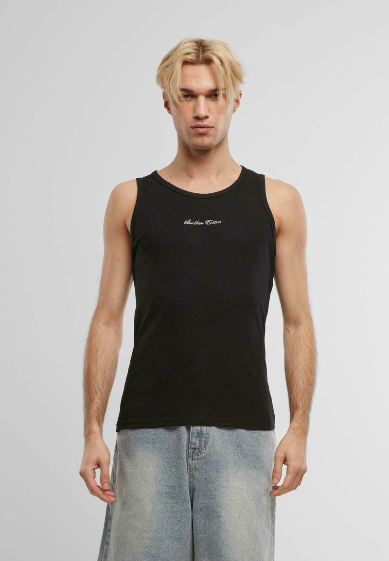 Svart bomullstopp med rund hals, som har en liten hvit brodert logo på brystet og brukes sammen med lyseblå denimshorts.