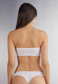 Top bandeau blanco sin costuras y bikini a juego, tejido suave, cinturas elásticas, diseño minimalista, textura suave, vista trasera.
