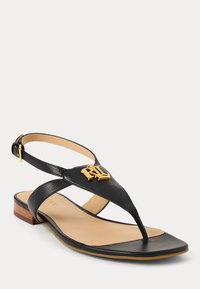 Μαύρη δερμάτινη σαγιονάρα με χρυσή λογότυπο λεπτομέρεια, επίπεδη σόλα, ανοιχτό σχέδιο, ρυθμιζόμενη θηλιά και μικρό ξύλινο τακούνι.