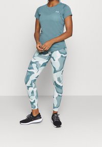 Teal tränings t-shirt i kombination med blå och vit kamouflageleggings. Svarta sportskor med snören och detaljer fulländar looken.