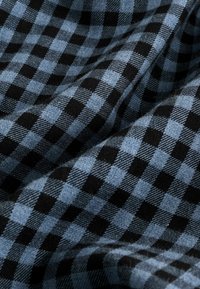 Black and light blue plaid fabric featuring a checkered pattern with varying square sizes, displaying a textured weave.