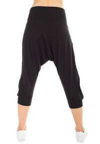 Pantalones harem negros hechos de una tela suave, con una amplia cinturilla elástica, longitud recortada y puños gather en los tobillos.