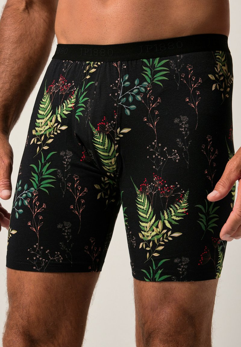 Černé boxerky vyrobené z měkké látky s botanickým vzorem, který zahrnuje zelené kapradiny, červené bobule a jemné květinové akcenty.