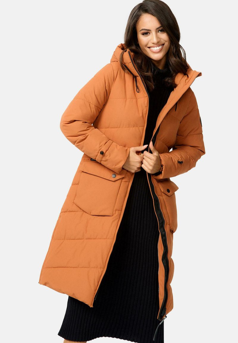 Long orange puffer coat with a hood, full-length zipper, snap closures, and front pocket. Worn over a ribbed black sweater dress.