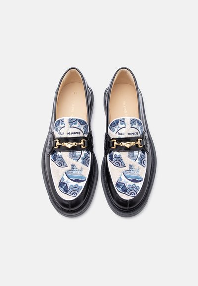 Μαύρα μοκασίνια με υφασμάτινο σχέδιο σε μπλε και κρεμ αποχρώσεις, διακοσμημένα με χρυσή αλυσίδα, με λείο δερμάτινο περίγραμμα και στρογγυλή μύτη.