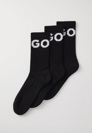 Schwarze Baumwollsocken, gerippetes Design, mit dem Wort "GO" in weißen Buchstaben auf der Oberseite. Drei Paare übereinander gestapelt.