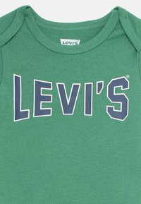Green cotton onesie featuring a navy "LEVI'S" logo. The round neckline has a ribbed texture with short sleeves.