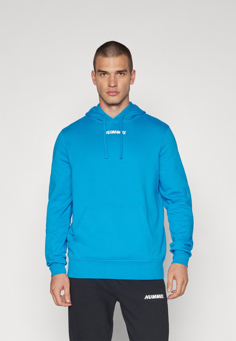 Felpa con cappuccio di un vivace blu, realizzata in tessuto morbido. Presenta una tasca frontale e un logo bianco sul petto. Vestibilità casual.