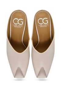 Mule din piele bej cu vârf ascuțit și un design distinctiv cu decupaje. Interiorul are o branț de culoare maro cu logo-ul "CG". Textură netedă.