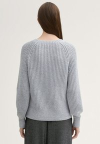 Maglione grigio a maglia grossa con maniche raglan, polsini e orlo a coste, che mostra un motivo tessuto e testurizzato. Vista dal retro.