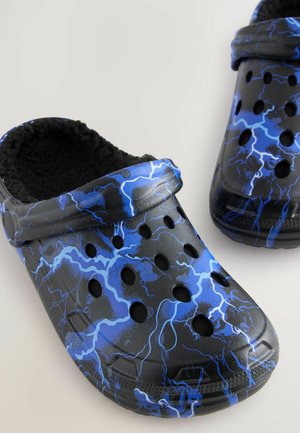 Saboti negri și albaștri cu un model de fulger, fabricați din material sintetic, având orificii de ventilație și o căptușeală moale.