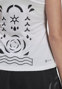 Top performance bianco con design grafico nero, caratterizzato da forme e motivi astratti. Tessuto testurizzato, logo "HEAT.RDY" sull'orlo.