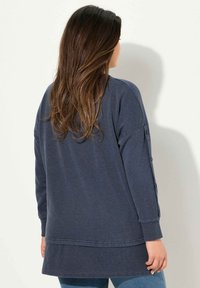 Maglietta a maniche lunghe blu Navy con vestibilità ampia, dettagli a bottoni sulle maniche e orlo dritto, realizzata in morbido cotone.