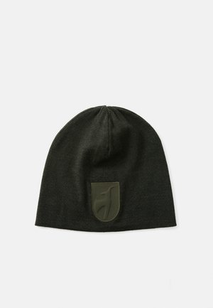 Gebreide beanie in donkergroen, met een textielstructuur en een rubberen logo-opdruk op de voorkant. Vormgegeven om strak om het hoofd te passen.